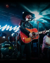 a man in a cowboy hat singing and playing an acoustic guitar